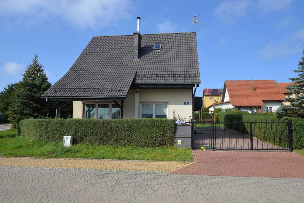 a house with a black roof and a fence at Villa Andre in Jarosławiec