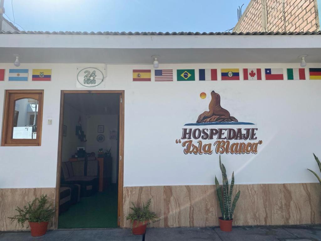 a white building with a sign that reads hospitable little bear at ALOJAMIENTO ISLA BLANCA in Paracas