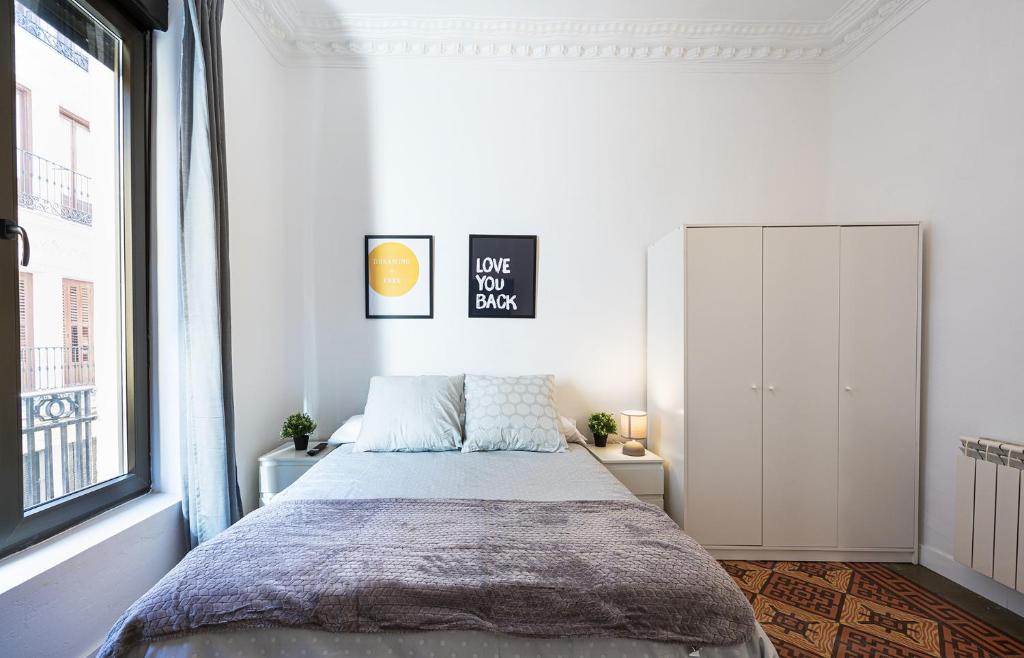 ein Schlafzimmer mit einem Bett und einem großen Fenster in der Unterkunft Antón Rooms in Madrid