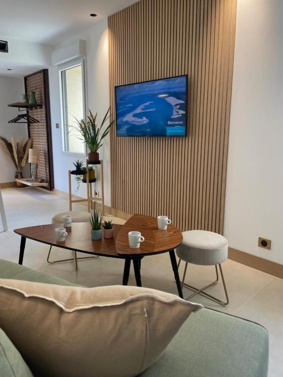 Appartement Neuf et Design في Camarsac: غرفة معيشة مع طاولة وتلفزيون على الحائط