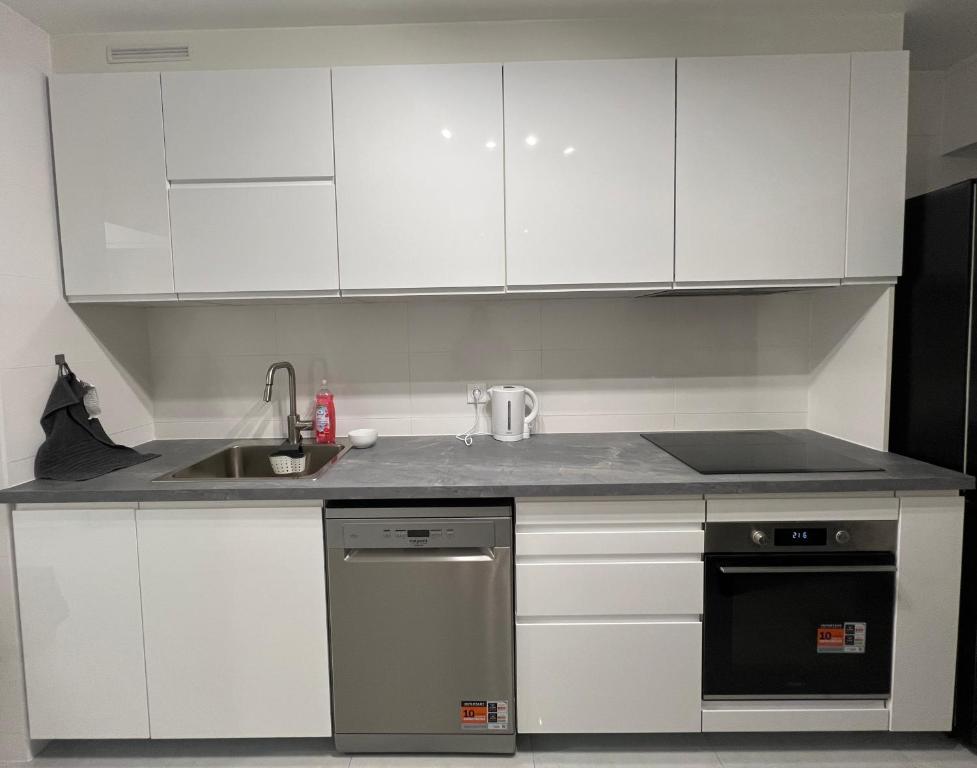 cocina con armarios blancos, fregadero y lavavajillas en Appartement récemment rénové à 1min du métro, en Créteil
