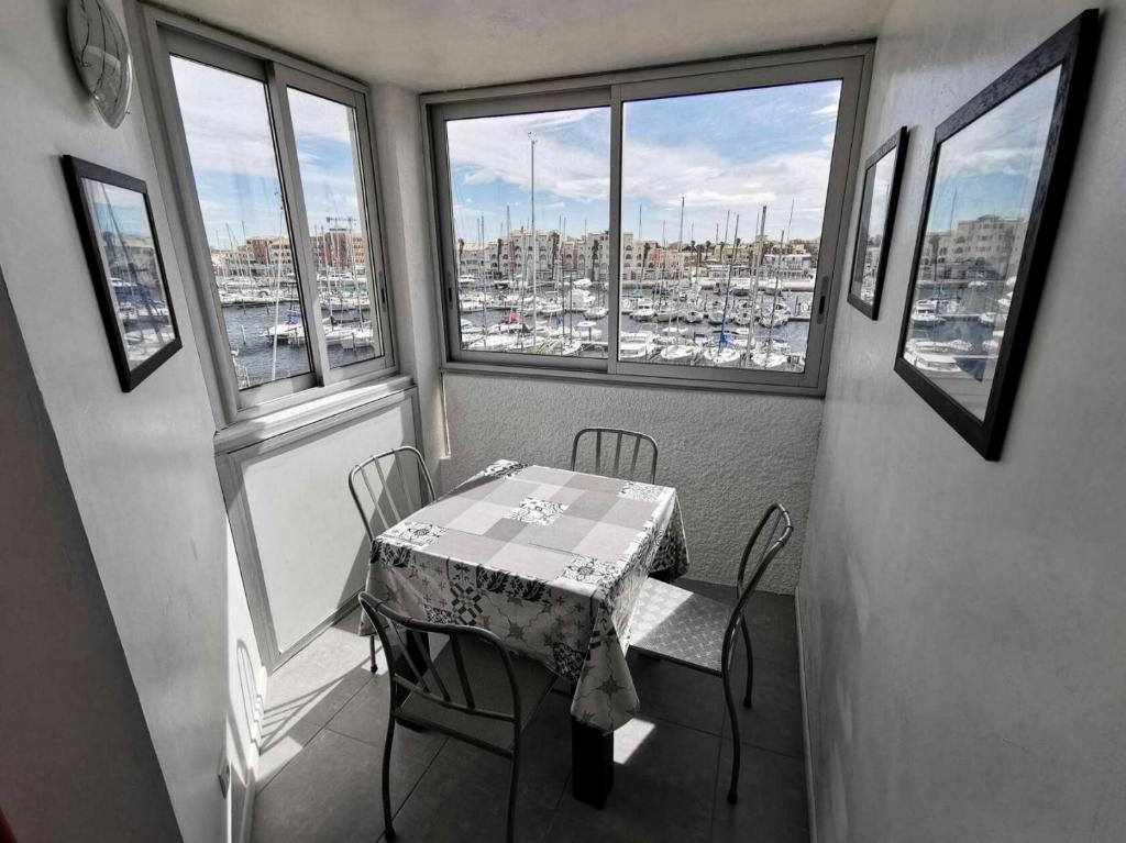 une table et des chaises dans une pièce avec des fenêtres dans l'établissement Résidence Le Grand Large - 2 Pièces 4 couchages PORT LEUCATE MAE-5074, à Port-Leucate