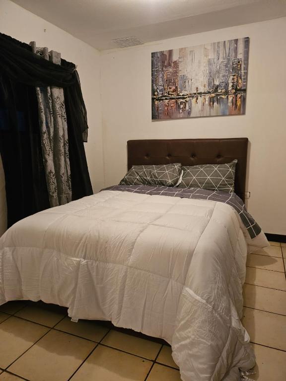 1 dormitorio con 1 cama con edredón blanco en cerca aeropuerto tobias bolaños en San José