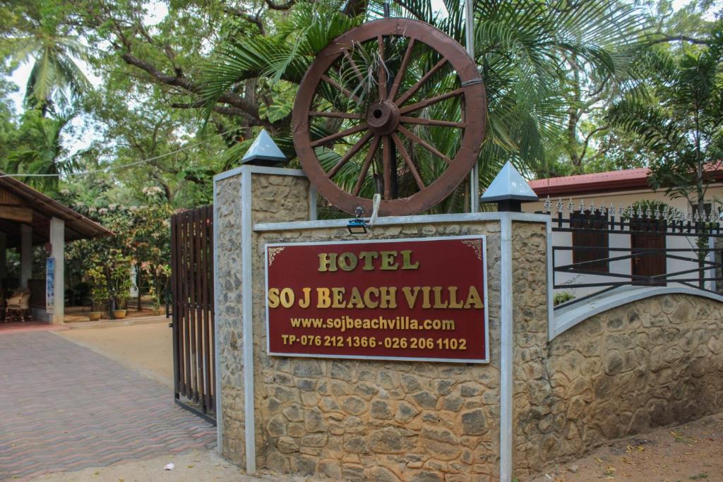 een bord voor een hotel met een groot wiel aan een muur bij So-J Beach Villa in Trincomalee