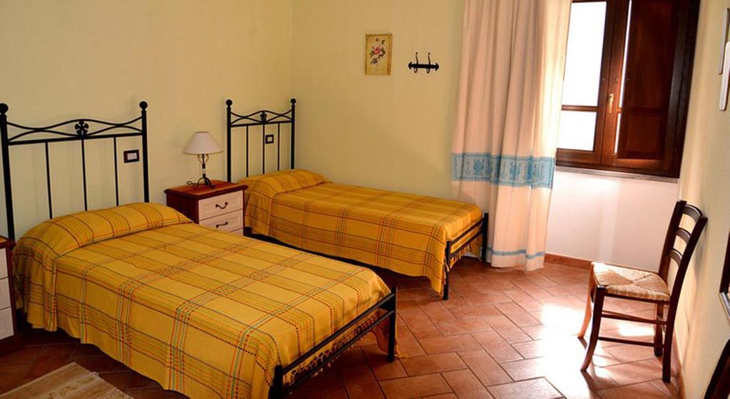 1 dormitorio con 2 camas, silla y ventana en B&B Sa Prama, en Galtellì