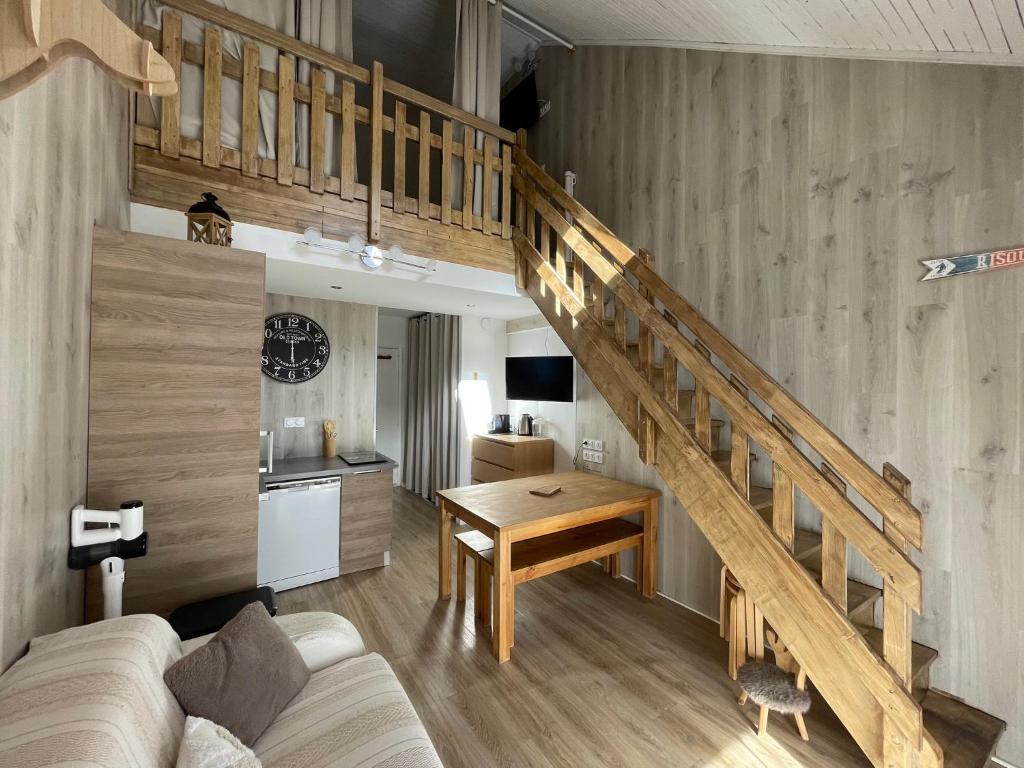 a living room with a staircase with a couch and a table at Risoul 1850 Beau Duplex pour 6 pers en plein centre de la station in Risoul