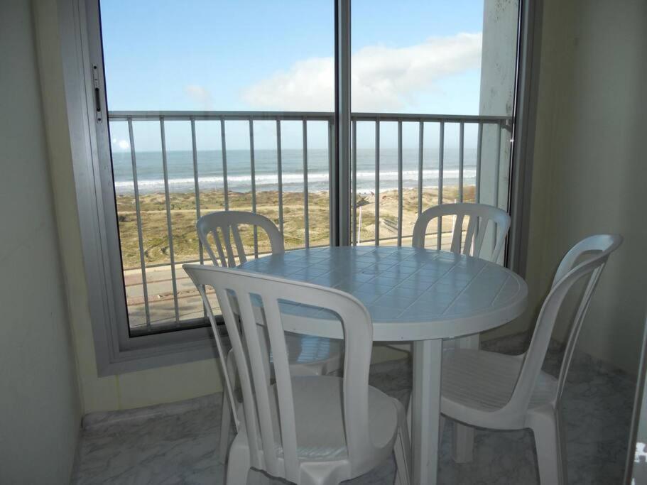 - une table et des chaises devant une fenêtre donnant sur l'océan dans l'établissement Appartement belle vue sur mer - 4425, à Soulac-sur-Mer