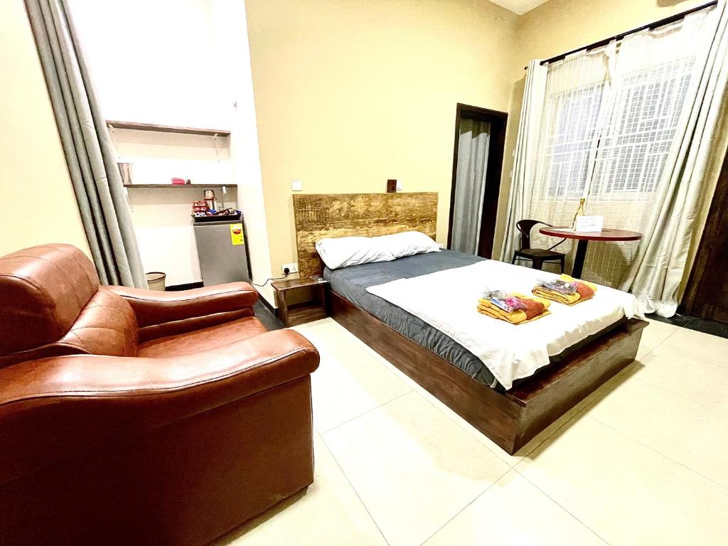 um quarto com uma cama, um sofá e uma cadeira em Accra Luxury Apartments At The Sanga Estates em Acra