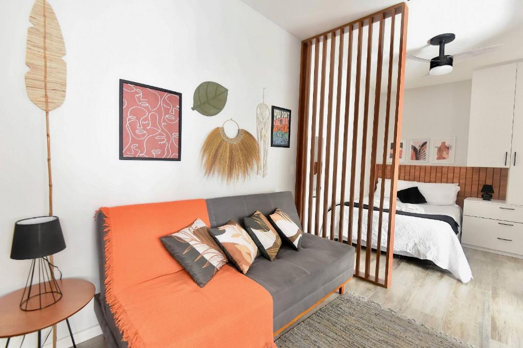 een woonkamer met een oranje bank en een bed bij Ótima localização, com vaga, piscina e Wi-Fi in Sao Paulo