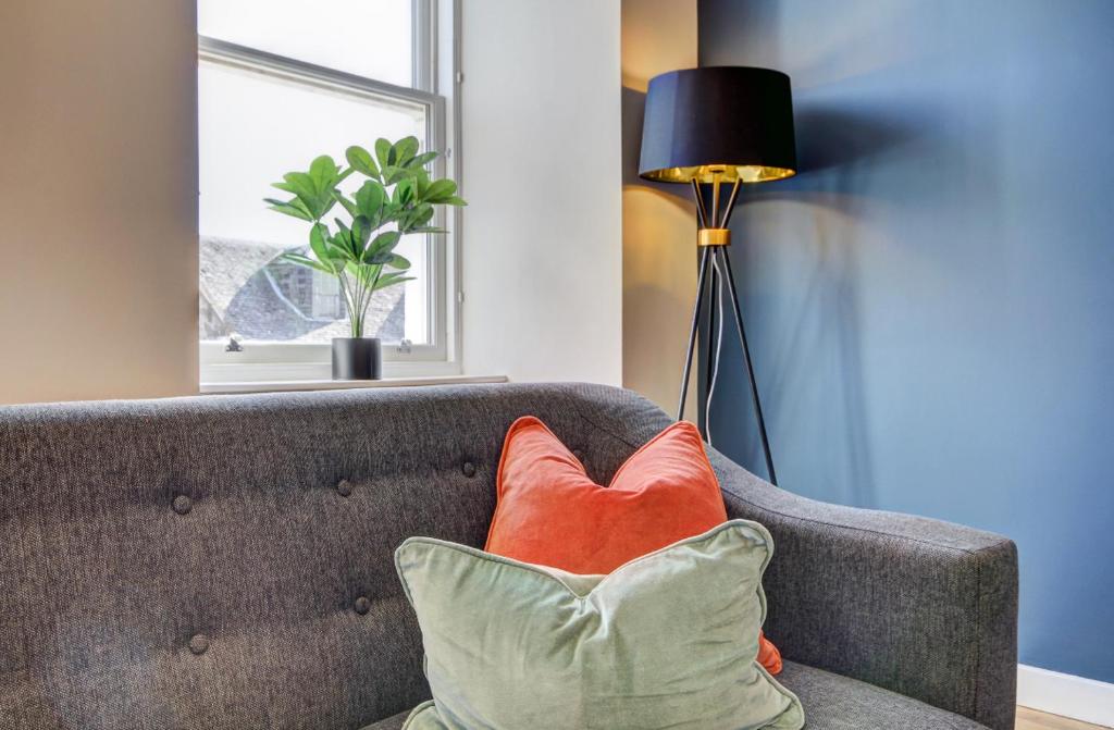 um sofá com uma almofada e um candeeiro num quarto em Coorie Doon - Aparthotel - Troon em Troon