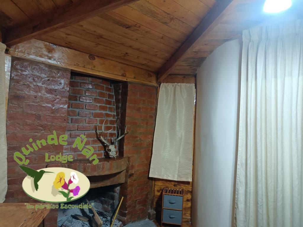 ein Wohnzimmer mit einer Ziegelwand und einem Kamin in der Unterkunft Quinde Ñan Lodge in Papallacta