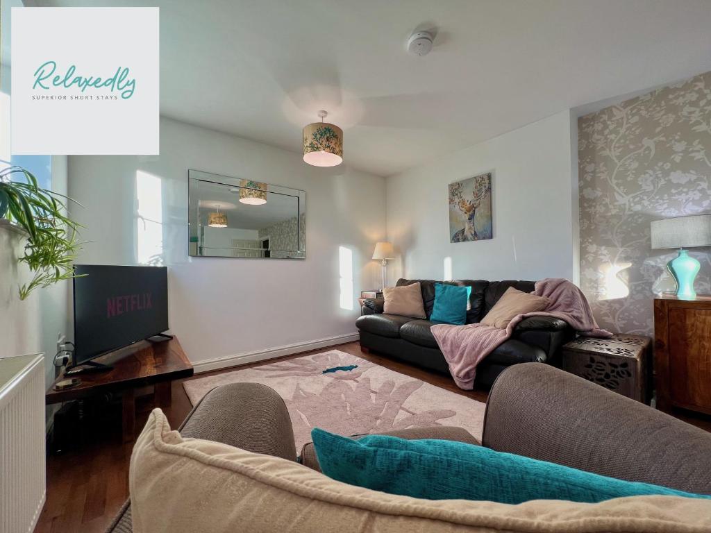 a living room with a couch and a tv at The Orchid-Central Beeston-Private Apartment-SmartTV-Free Wi-Fi-Tram-Parking in Nottingham