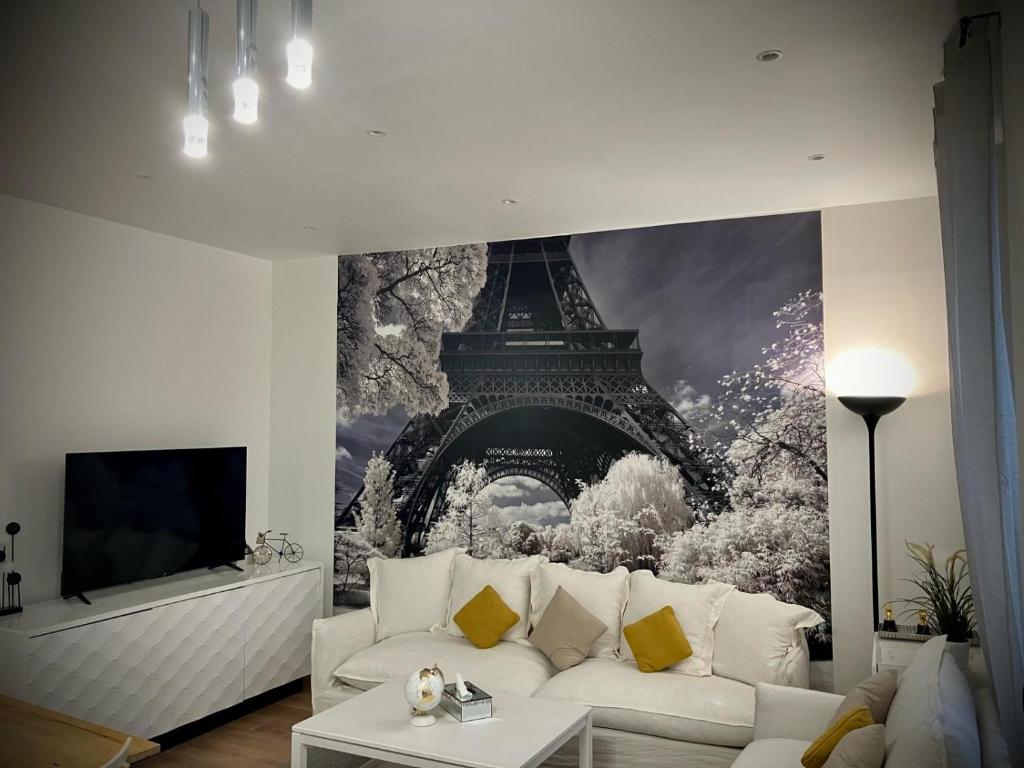 a living room with a white couch in front of the eiffel tower at PARIS CITY-Le Raincy - Facing station - 4 to 8 Pers in Le Raincy