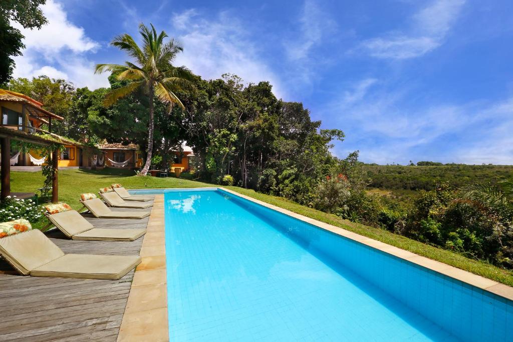 a swimming pool with lounge chairs next to a house at Casa Baiana Pousada & Aconchego in Trancoso