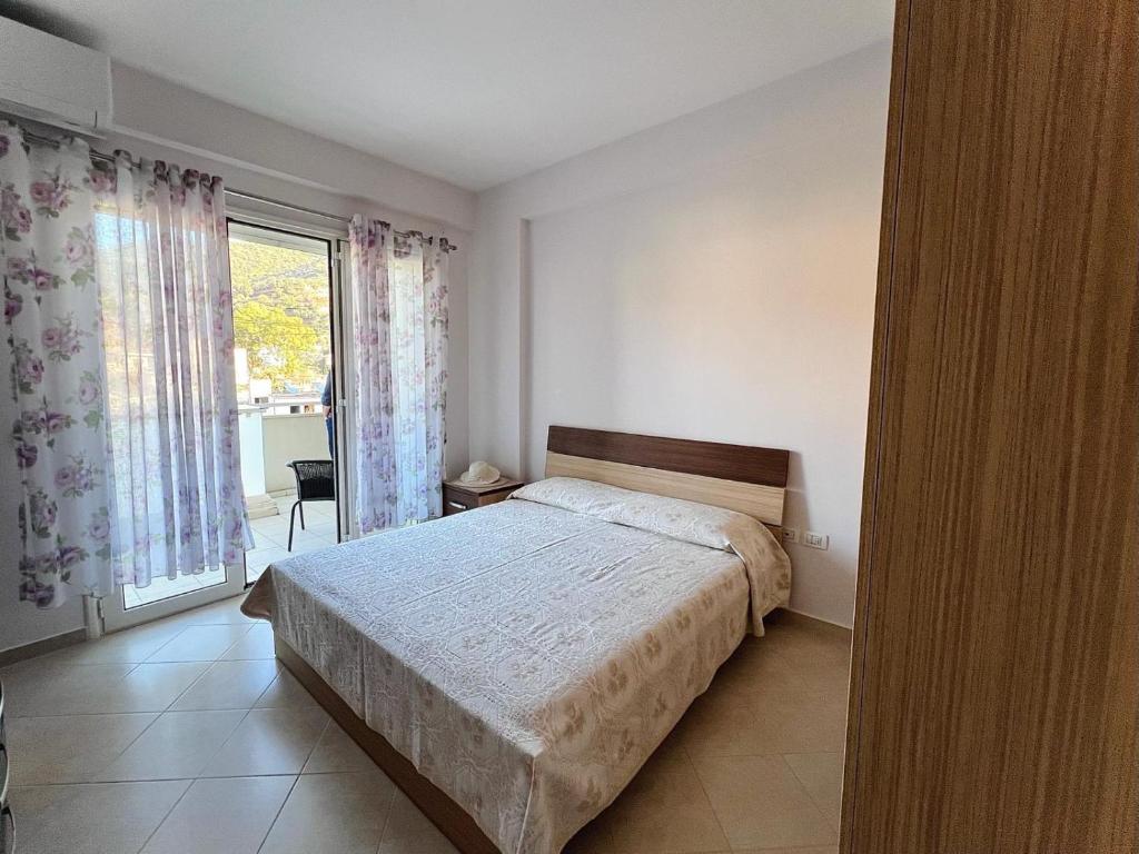 um quarto com uma cama e uma grande janela em DESA Seaside Apartment em Vlorë