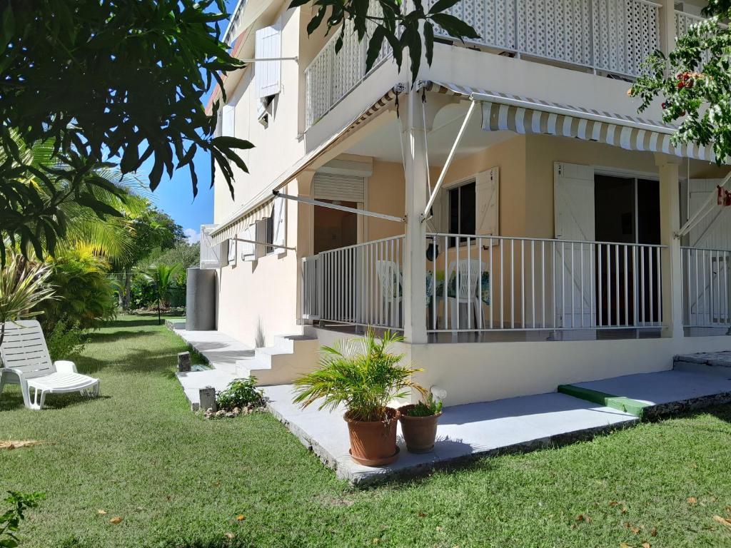 a house with a porch and some plants in the yard at T2 Bas de villa Les Hibiscus in Sainte-Anne