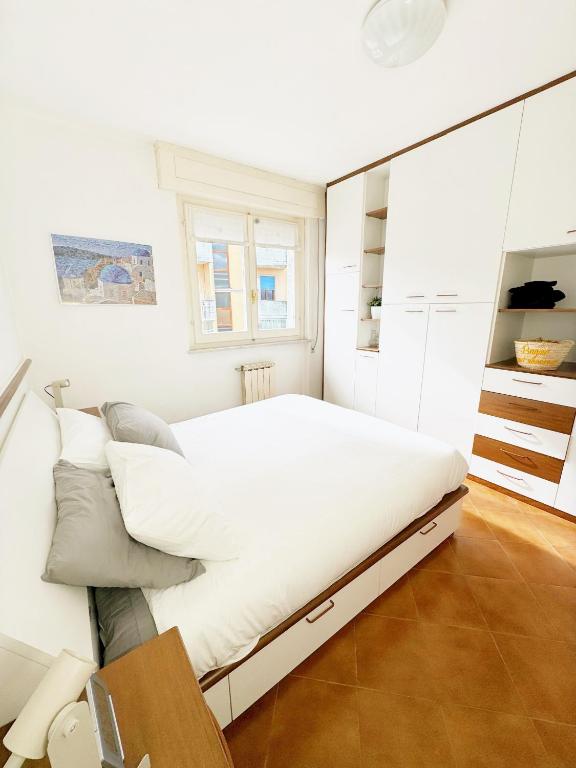 a white bedroom with a large bed and a mirror at Luminoso, Versilia, Vicino al Mare in Marina di Carrara