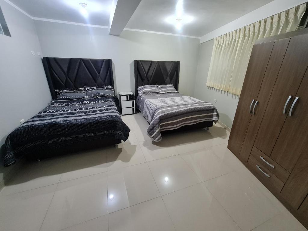 2 łóżka w pokoju z białymi kafelkami w obiekcie Wilder host w mieście Puno