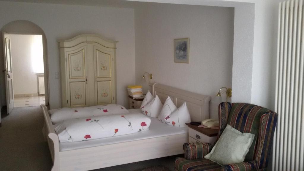 a bedroom with a white bed and a chair at Hotel Schlossgarten in Gladenbach