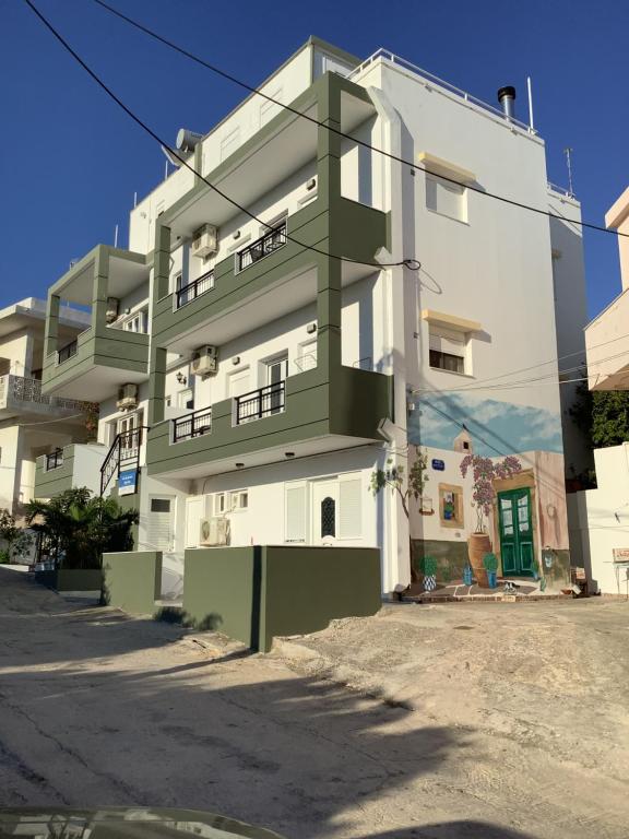 een groen en wit appartementencomplex in een straat bij Blue Sky Apartments I in Makry Gialos