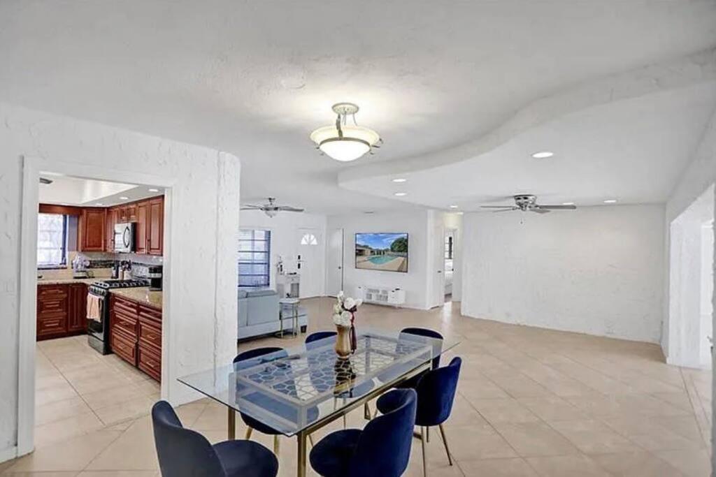 a dining room and kitchen with a glass table and chairs at Stylish palm beach home with pool and office in Palm Beach Gardens