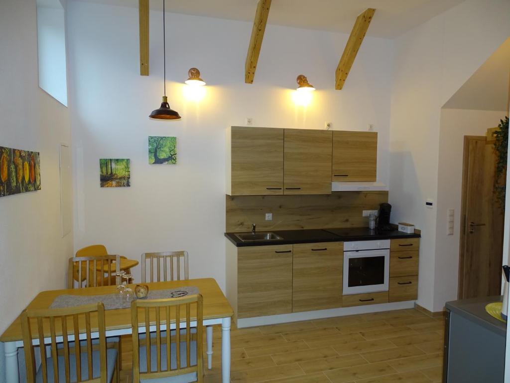 kuchnia z drewnianymi szafkami i stołem z krzesłami w obiekcie Ferienwohnung Schusternagerl w mieście Simbach