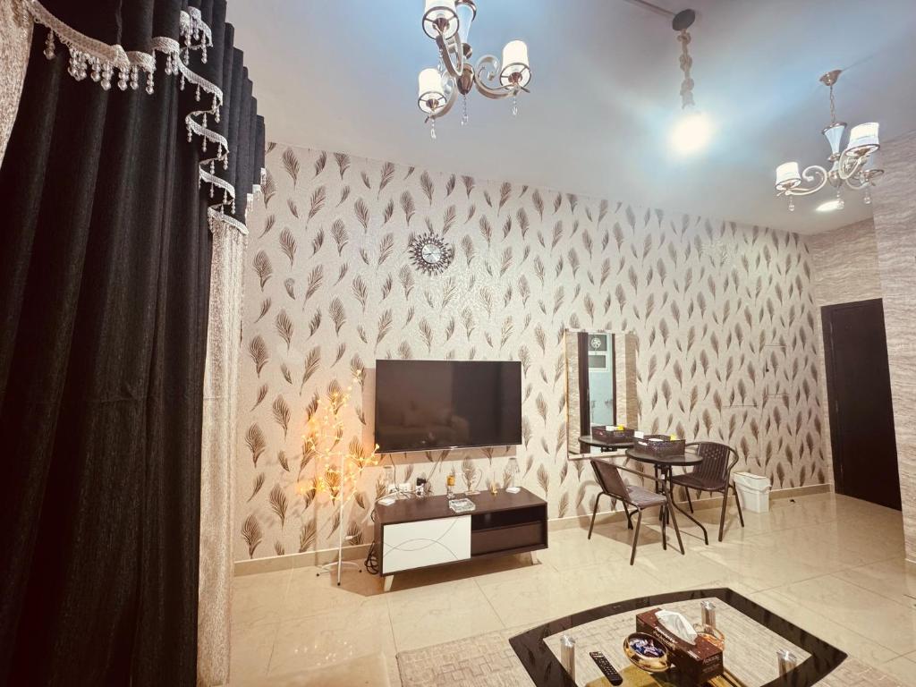 a living room with a television on a wall with a table at Beautiful home in Ajman 