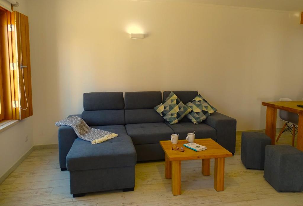 SWEET HOME MILFONTES by Stay in Alentejo في فيلا نوفا دو ميلفونتيس: غرفة معيشة مع أريكة زرقاء وطاولة قهوة