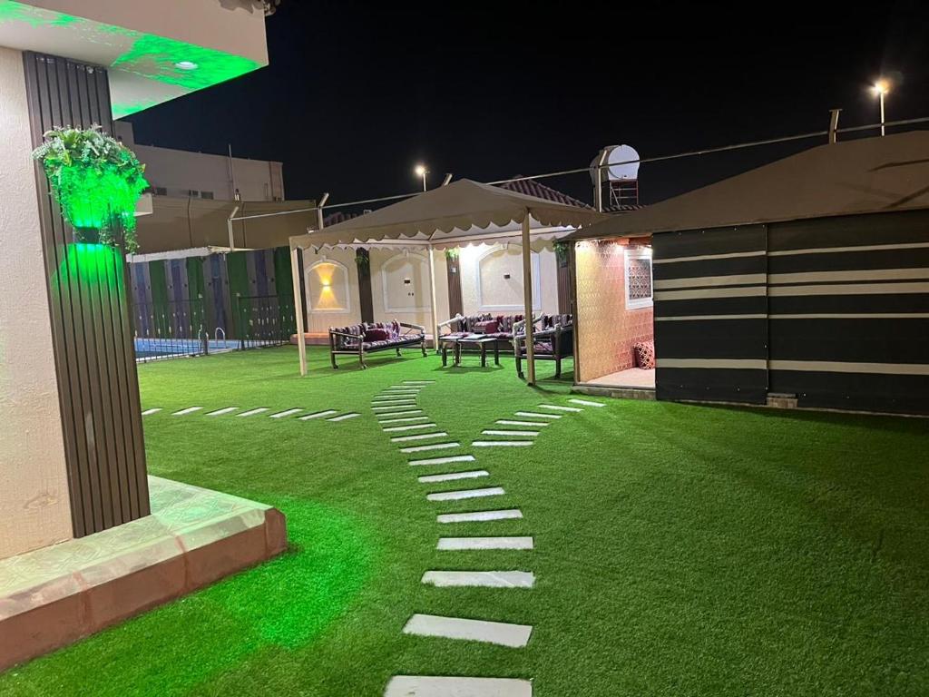 a garden at night with a green lawn at شالية سحاب in Al Madinah