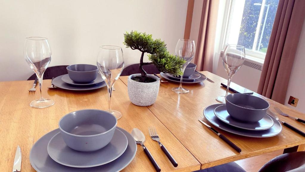einen Holztisch mit Tellern und Weingläsern darauf in der Unterkunft UK CHAPS Retreat: 2 Bedroom - 2Bathroom Apartment in London