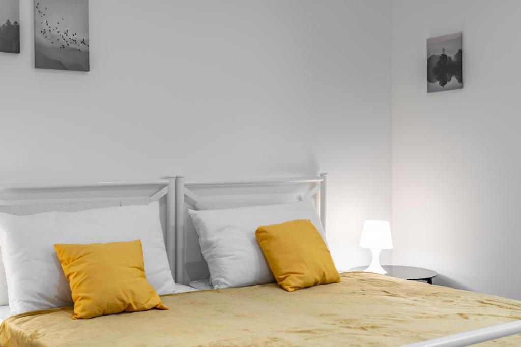 a bedroom with a bed with two yellow pillows at Cascina Conicchio - Metro Station - by Host4U in Brescia