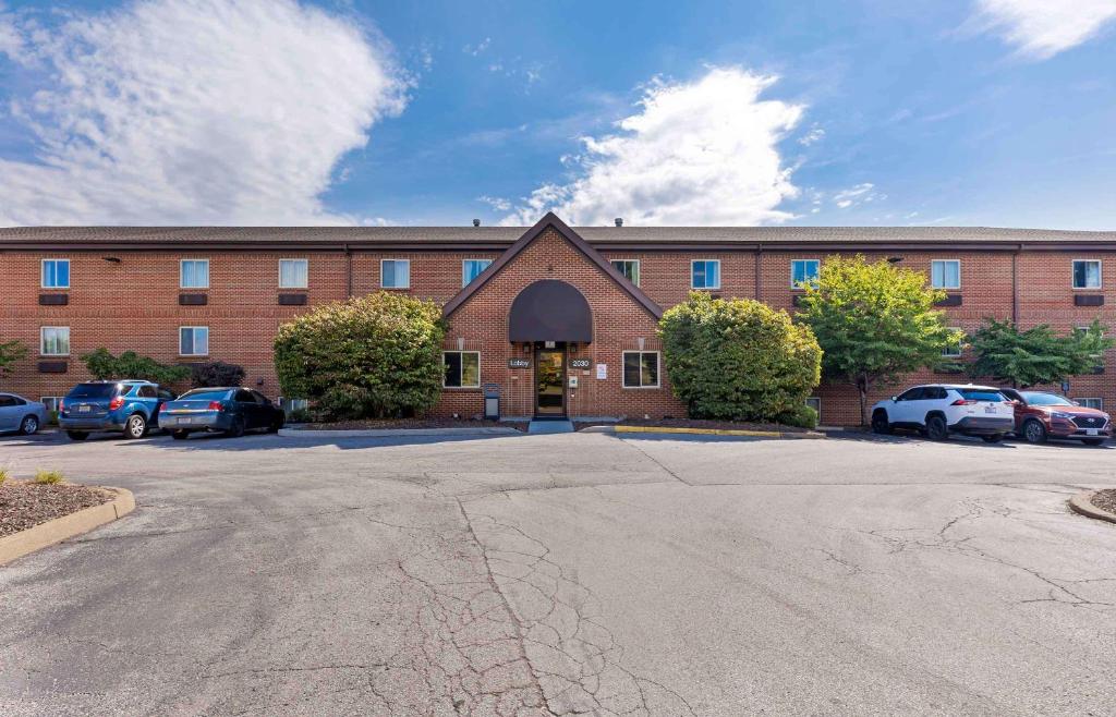 a large brick building with cars parked in a parking lot at Extended Stay America Select Suites - St Louis - Westport - Craig Road in Maryland Heights