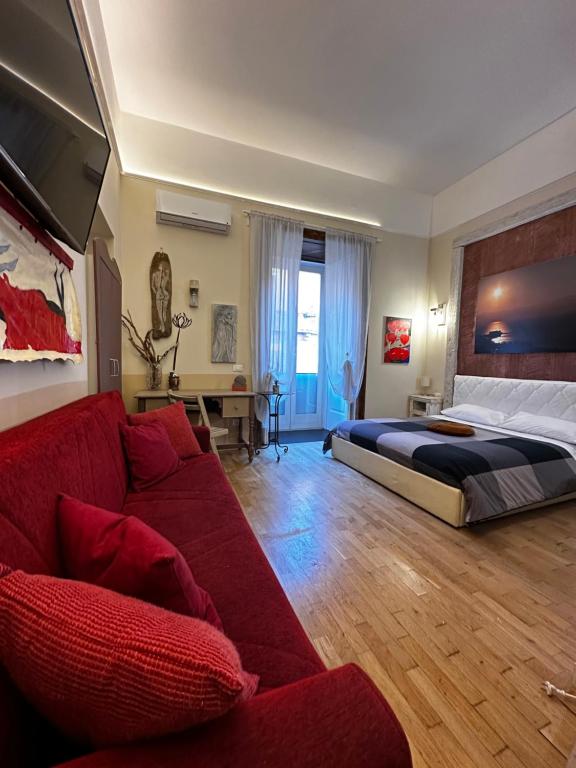 ナポリにあるCorso 211 Beds & Suitesのベッドルーム1室(ベッド1台、赤いソファ付)