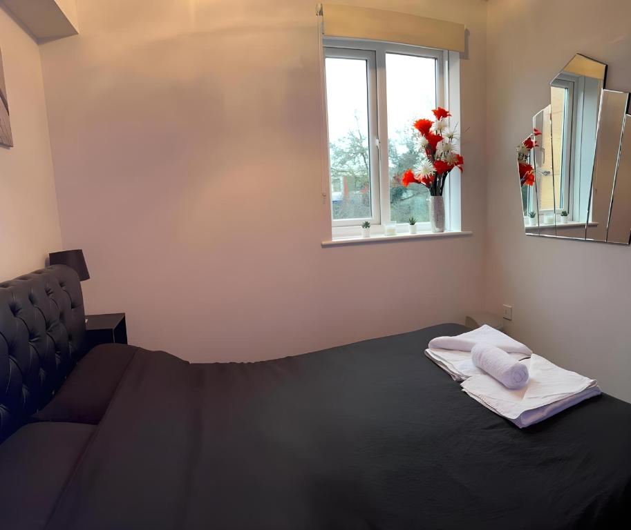 a bedroom with a black bed and a window at Sleek & Stylish - E15 Apartment With Parking in London
