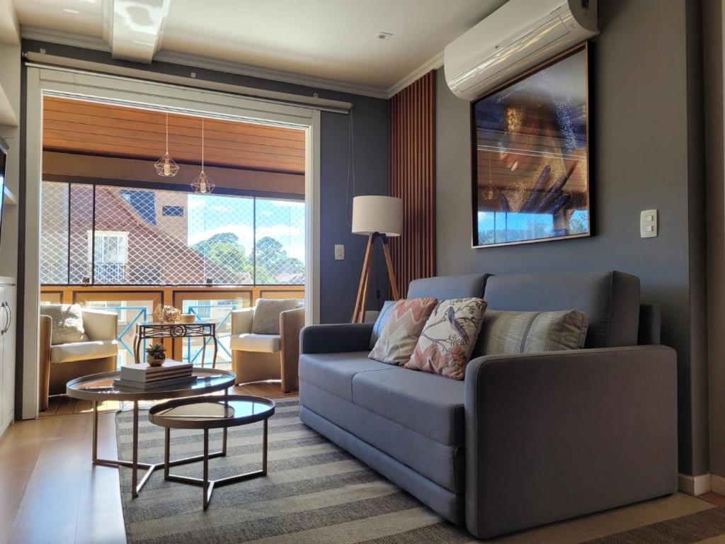 uma sala de estar com um sofá e uma mesa em Lindo Apartamento a 1 Quadra da rua Coberta em Gramado