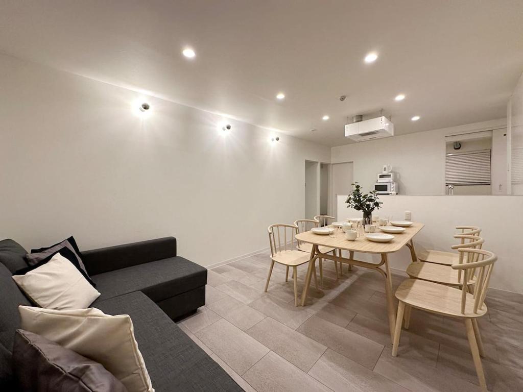 a living room with a couch and a table and chairs at bHOTEL Nikke - Apt for 10Ppl Ideal for Big Group in City Center in Ōsukachō