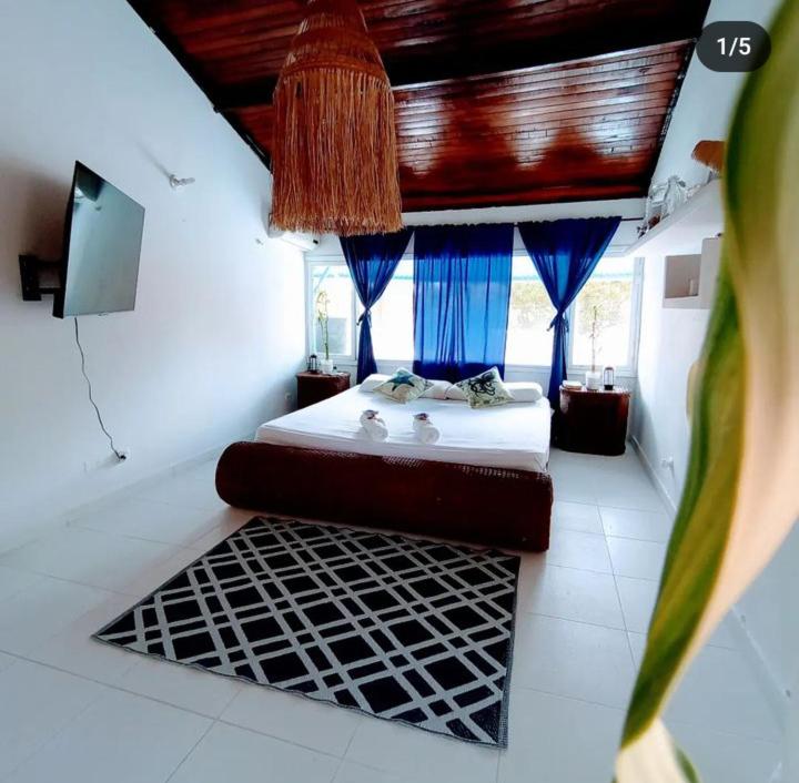 a bedroom with a bed with blue curtains and a television at Cabaña cerca a la playa, con piscina, en playa Mendoza atlántico. in Puerto Colombia
