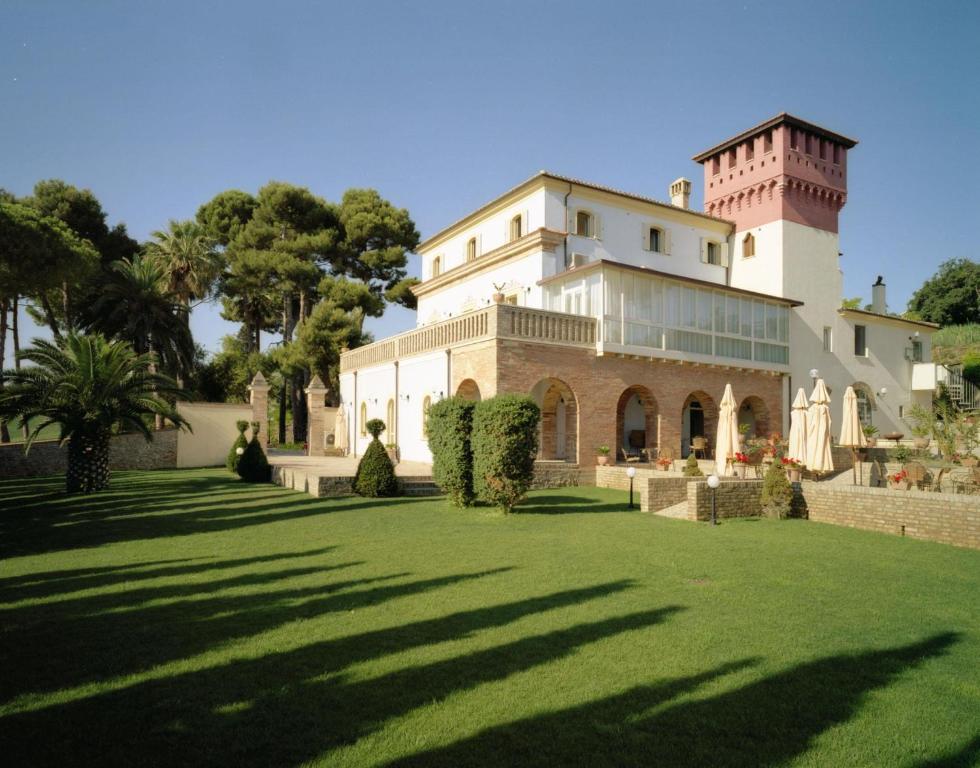 a large white house with a grass yard at Relais Villa Rossi in Silvi Marina