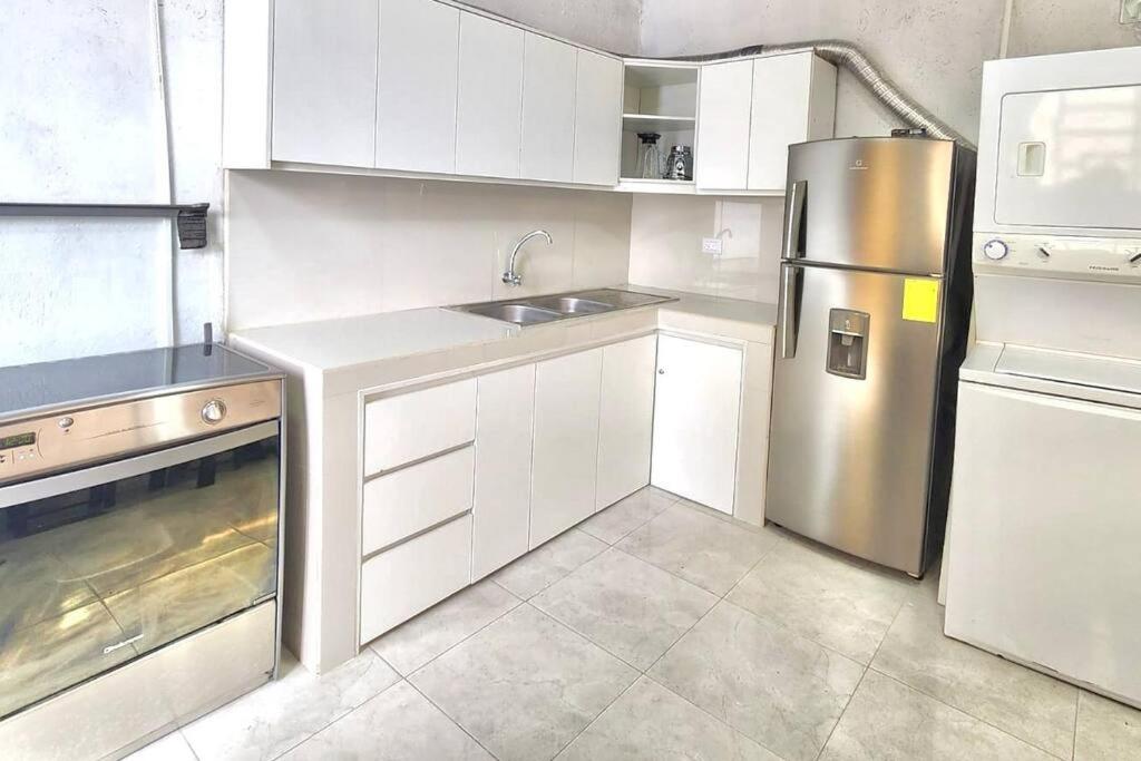 a kitchen with white cabinets and a stainless steel refrigerator at El refugio de los viajeros in Quito
