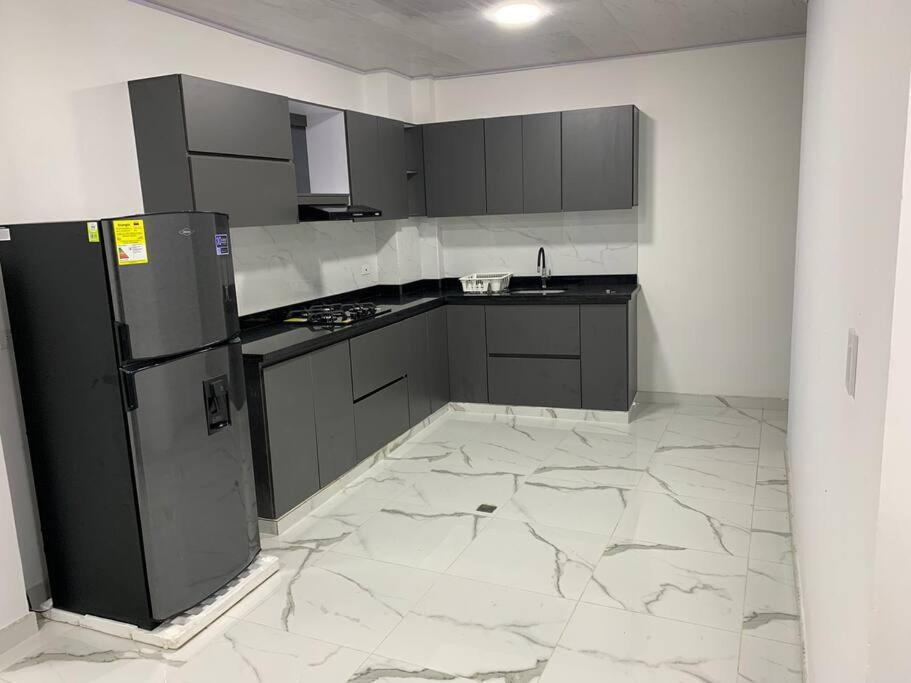 eine Küche mit einem schwarzen Kühlschrank und Marmorböden in der Unterkunft Apartamento de descanso in La Dorada