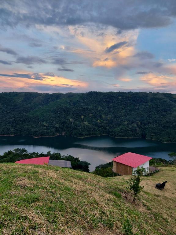 a barn on a hill with a view of a lake at COCOZNA Glamping in Norcasia