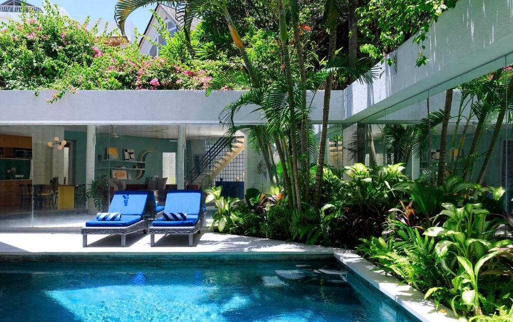 a swimming pool with two blue chairs next to a house at Villa Ungava in Seminyak