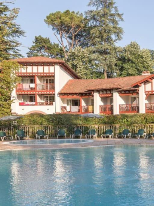 un bâtiment avec une piscine en face d'une maison dans l'établissement 1-Appt avec piscine à St-Jean Pays-Basque, à Uhart-Cize