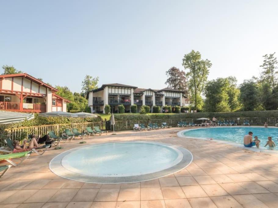 ウアール・シーズにある1-Appt avec piscine à St-Jean Pays-Basqueの周りに座っている人々がいるリゾートのプールを利用できます。