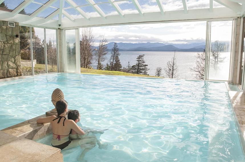 dos personas sentadas en una gran piscina en Pailahue Cabañas Lodge en San Carlos de Bariloche
