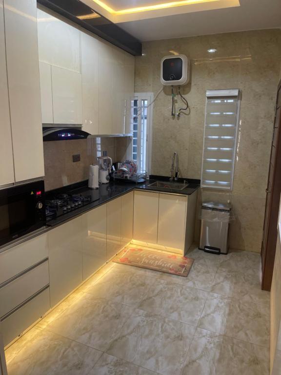 uma cozinha com armários brancos e uma televisão na parede em Majorstone Luxury Apartment em Ibadan