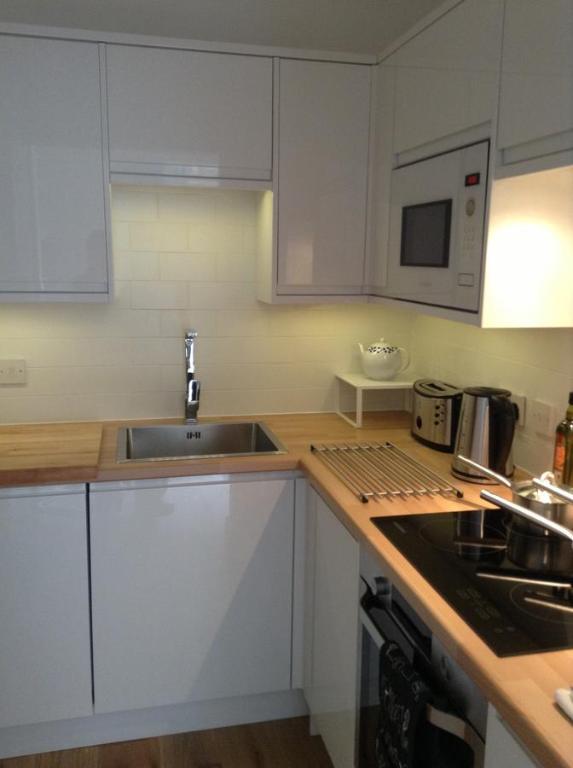 a kitchen with white cabinets and a sink and a microwave at 7 Mount Sion in Royal Tunbridge Wells