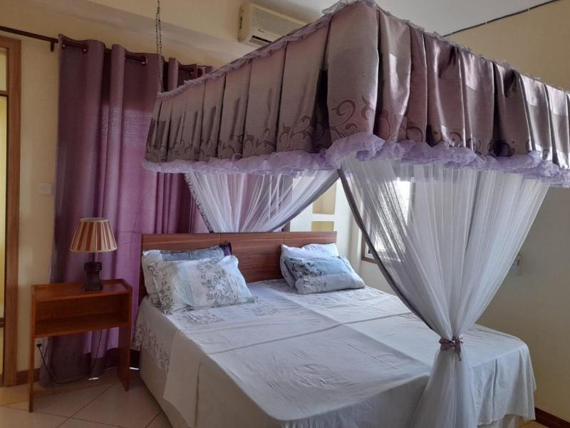 a bedroom with a bed with a canopy and curtains at Serena Beach View Apartment in Mombasa