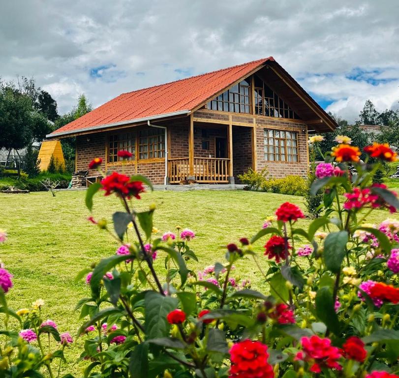 ein Haus mit roten Blumen davor in der Unterkunft Cabañas Tecla María in Otavalo