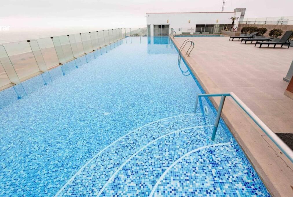 a swimming pool with a water slide in front of the beach at Departamento con vista al mar in Lima